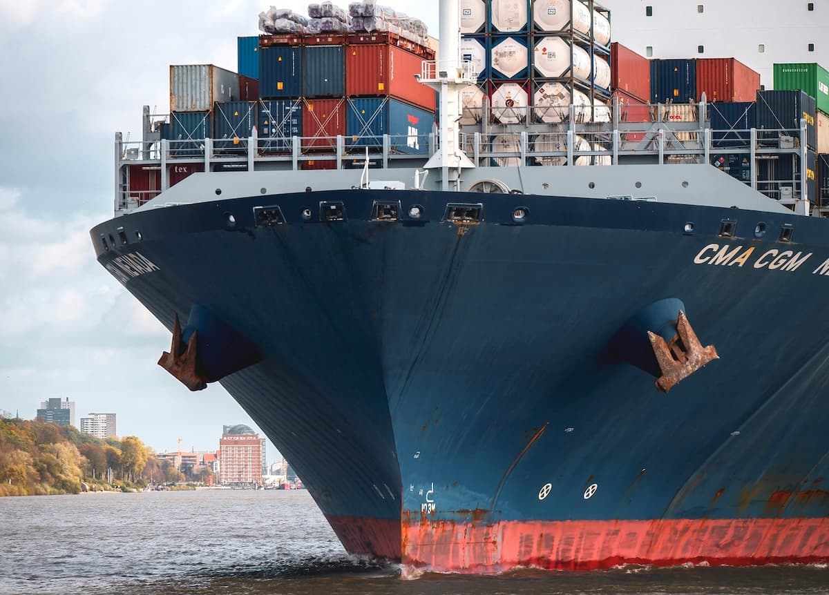 Bow of a CMA CGM container ship on the water, stacked with shipping containers